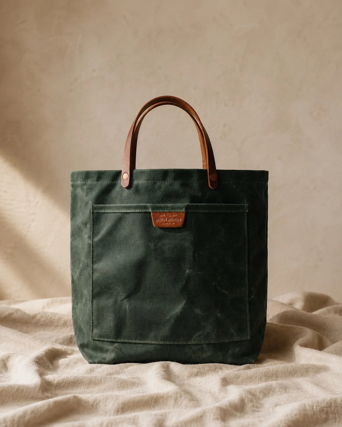 The Forest Coal Tote standing upright, showing its waxed-canvas body and leather handles.