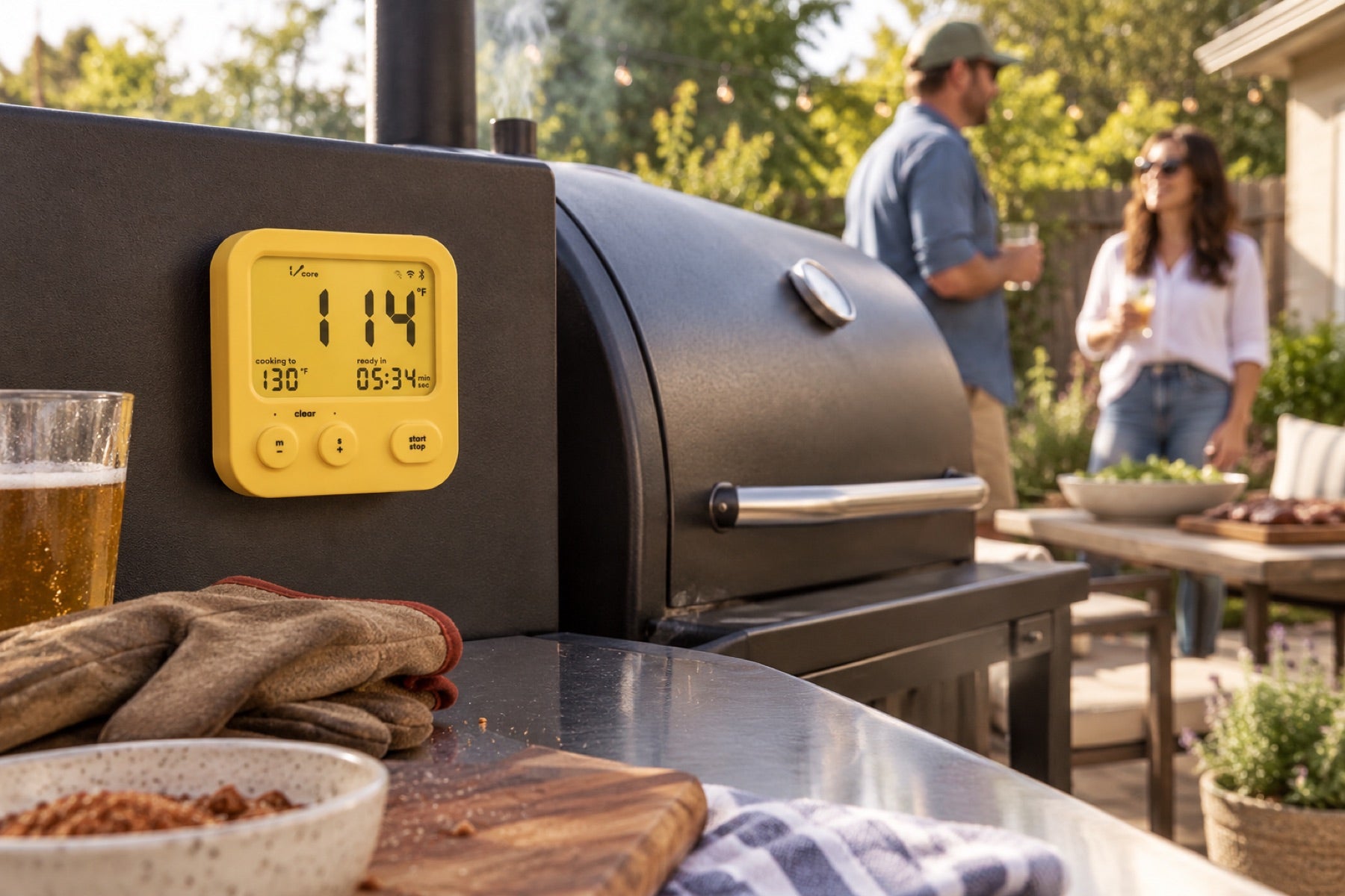 Combustion WiFi Display mounted beside a closed backyard smoker while friends relax nearby