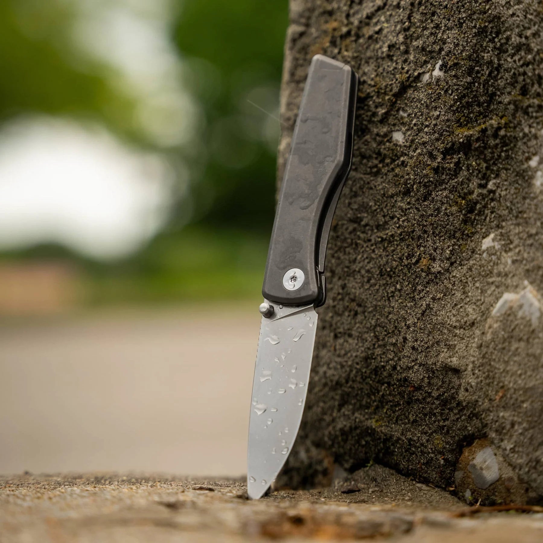 BIGiDESIGN Overlook titanium folding knife with water droplets on its open blade