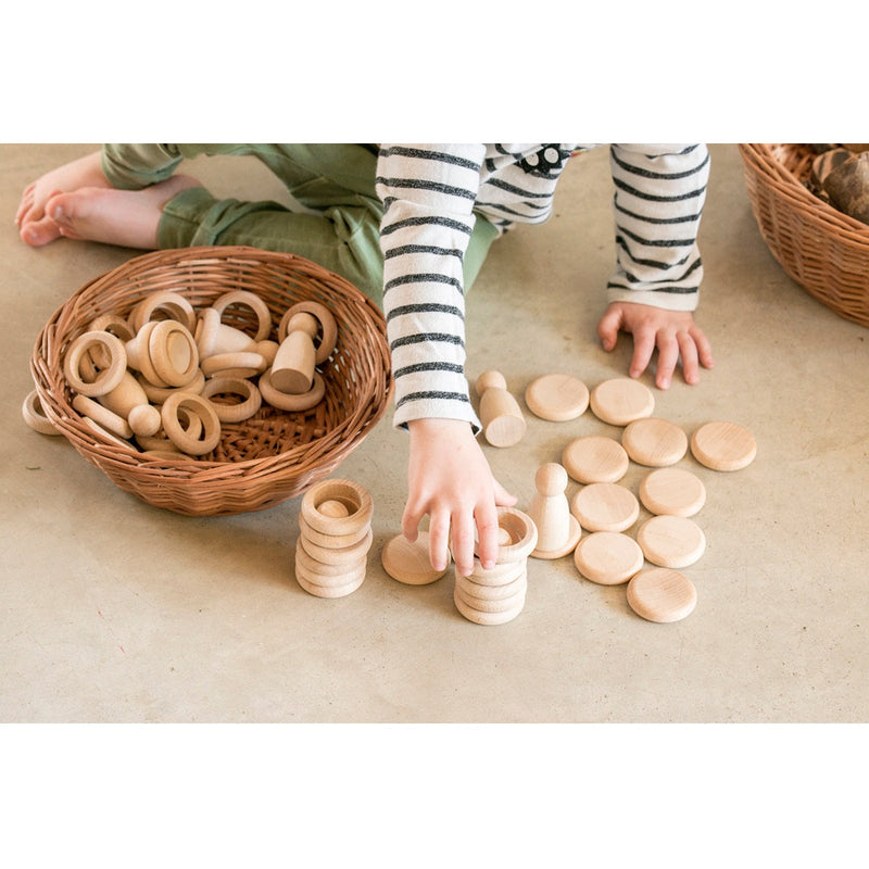 Child stacking Grapat Nins rings and coins in natural wood