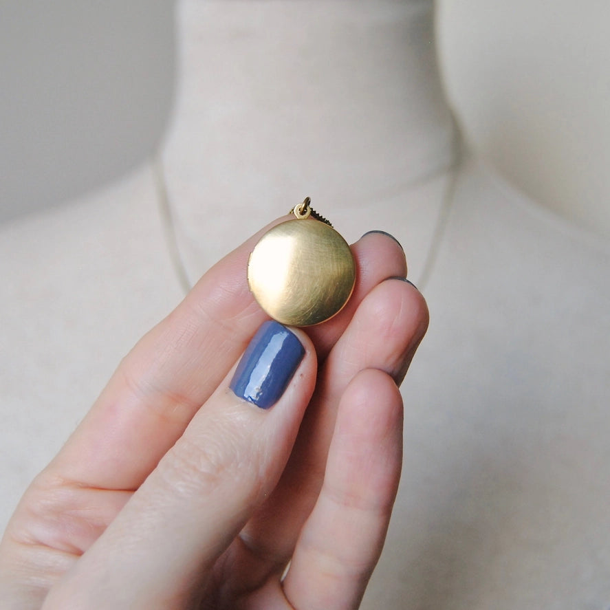 Closed round brass locket in hand