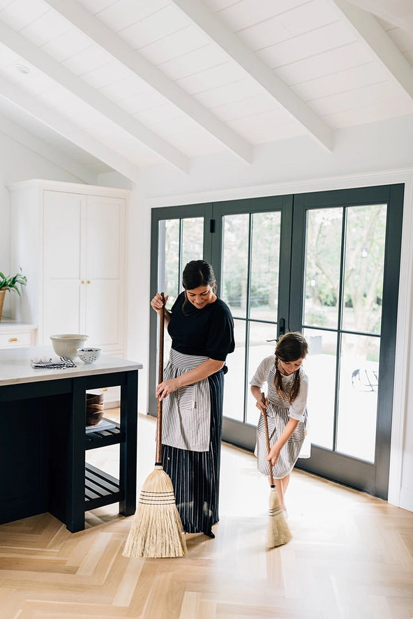 Mother and daughter with the broom on a farmhouse porch