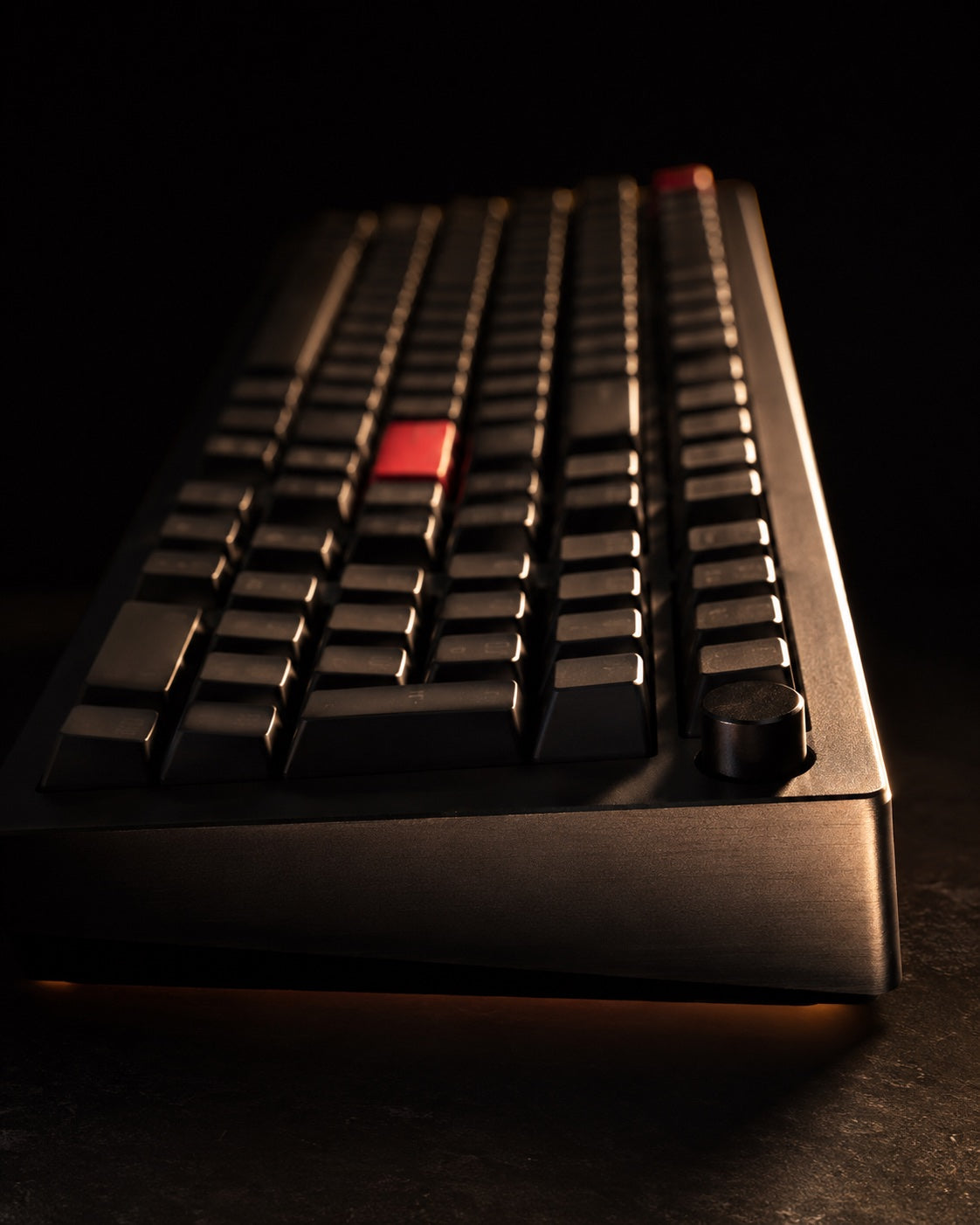 The Q5 Max's thick machined aluminum case wall, rim-lit in warm brass light.
