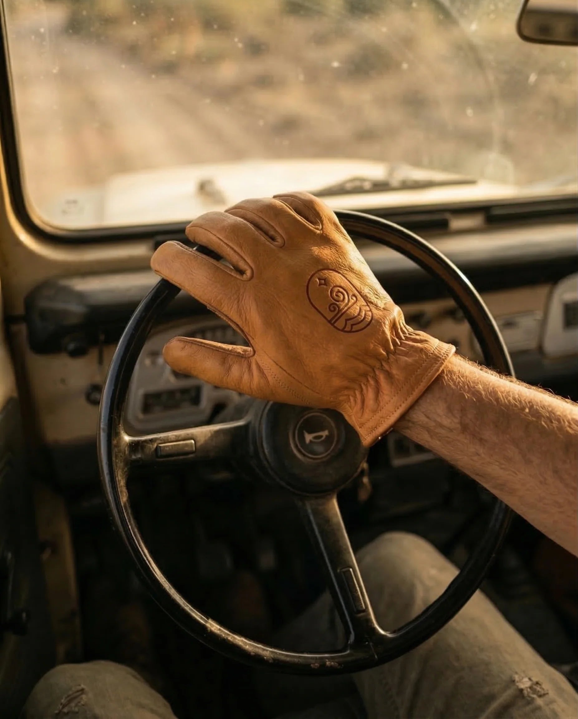 A buffalo leather glove resting on the steering wheel of a vintage truck