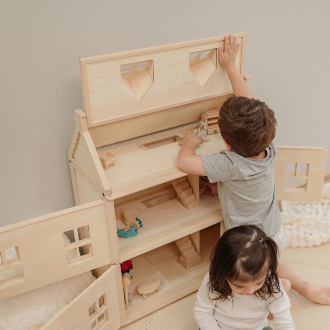 Children exploring the dollhouse’s opening roof and interior rooms