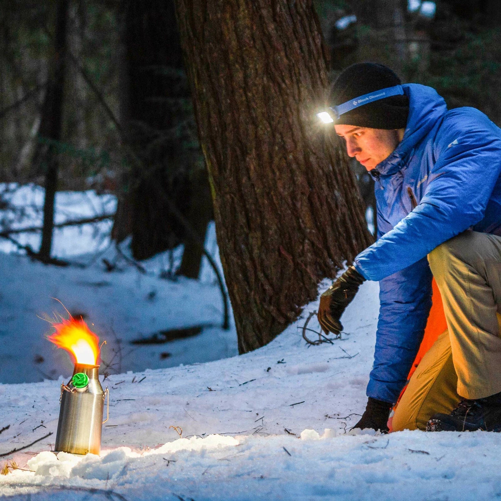 Camper feeding the Trekker fire-base by headlamp on a snowy night